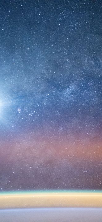 A bright airglow blankets Earth's horizon as the Milky Way illuminates the night sky
