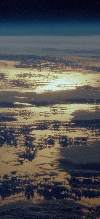 STS-36 Earth observation of sun beaming off cloud-covered ocean waters