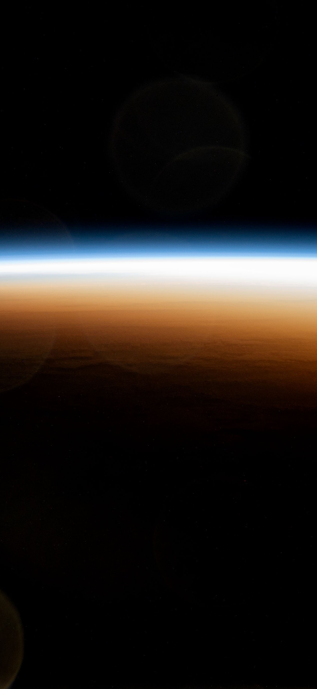 An orbital sunrise colorfully illuminates the Earth's atmosphere