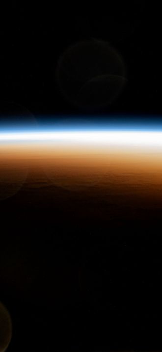 An orbital sunrise colorfully illuminates the Earth's atmosphere