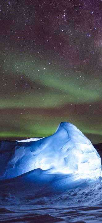 Aurora australis dancing over an LED illuminated igloo